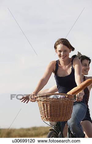 Young women on bikes on country road View Large Photo Image Stock Image - Young women on bikes on country road. Fotosearch