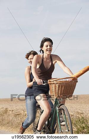 Young women on bikes on country road View Large Photo Image Stock Photography - Young women on bikes on country road. Fotosearch
