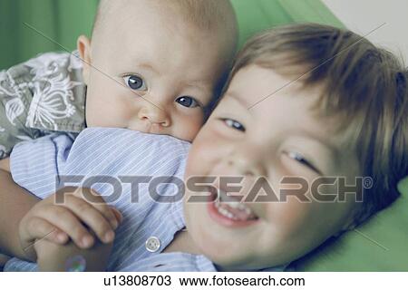 Stock Image - Baby boy and brother playing on couch. Fotosearch