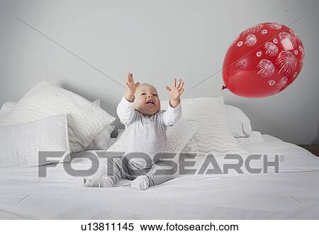 Baby boy playing with balloon on bed View Large Photo Image Stock Photography - Baby boy playing with balloon on bed . Fotosearch