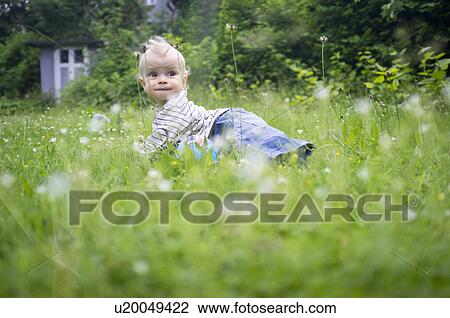 Stock Image - Baby girl crawling in tall grass. Fotosearch