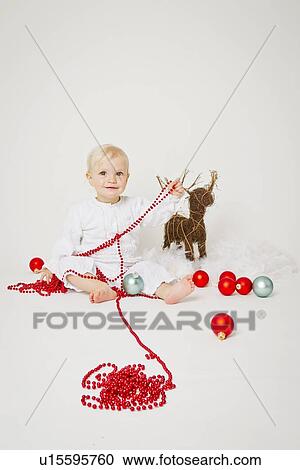 Stock Image - Baby girl holding Christmas ornaments. Fotosearch