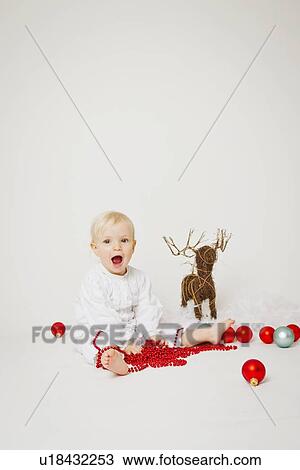 Stock Image - Baby girl holding Christmas ornaments. Fotosearch