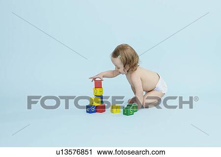 Stock Image - Baby girl playing with colored blocks. Fotosearch