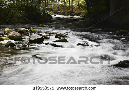 Stock Photography - Blurred view of river rushing over rocks. Fotosearch