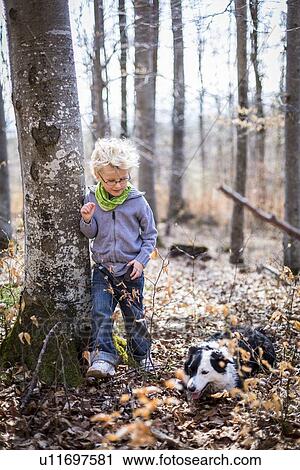 Stock Image - Boy and dog exploring in forest. Fotosearch