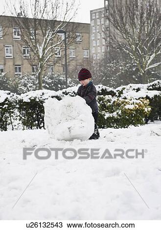 Boy building snowman in park View Large Photo Image Stock Image - Boy building snowman in park. Fotosearch