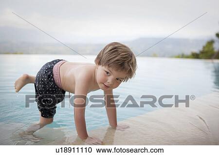 Stock Image - Boy climbing out of swimming pool. Fotosearch