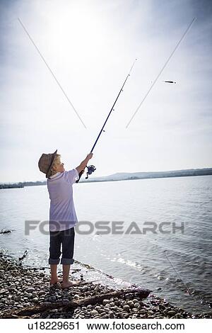 Stock Image - Boy fishing in shallow creek. Fotosearch