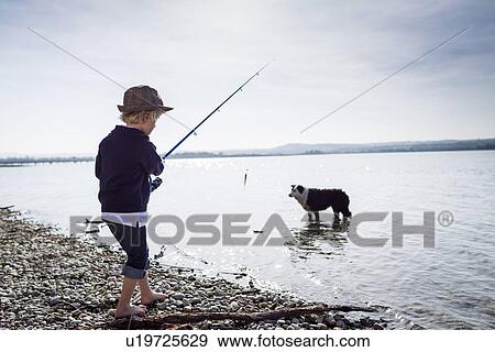 Stock Photo - Boy fishing with dog in creek. Fotosearch