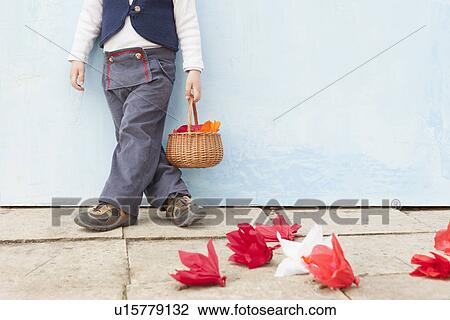 Stock Image - Boy holding basket of paper flowers. Fotosearch