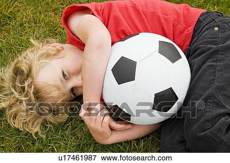 Stock Photo - Boy holding soccer ball in grass. Fotosearch