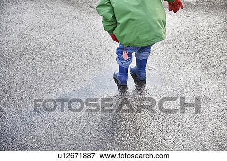 Boy in rain boots playing in puddle View Large Photo Image Stock Photo - Boy in rain boots playing in puddle. Fotosearch