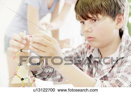 Stock Image - Boy making molecular model in class. Fotosearch