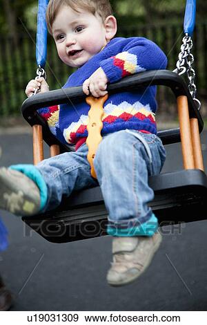 Boy playing in swing on playground View Large Photo Image Stock Photo - Boy playing in swing on playground. Fotosearch