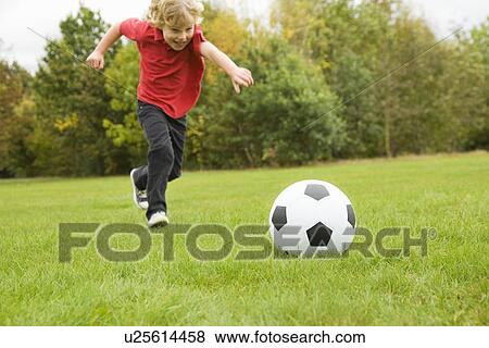 Boy playing with soccer ball in field View Large Photo Image Stock Photo - Boy playing with soccer ball in field. Fotosearch