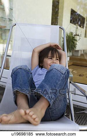 Stock Photography - Boy relaxing in deck chair on patio. Fotosearch