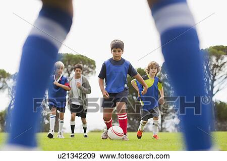 Boys playing soccer on pitch View Large Photo Image Stock Photo - Boys playing soccer on pitch. Fotosearch