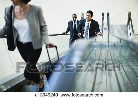 Business people riding escalator View Large Photo Image Stock Image - Business people riding escalator. Fotosearch