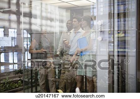Business people riding glass elevator View Large Photo Image Stock Photo - Business people riding glass elevator. Fotosearch