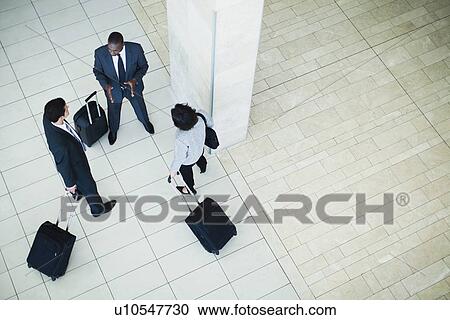 Business people rolling luggage in lobby View Large Photo Image Stock Image - Business people rolling luggage in lobby. Fotosearch