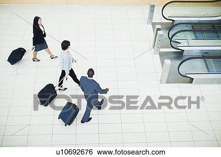 Business people rolling luggage in lobby View Large Photo Image Stock Photograph - Business people rolling luggage in lobby. Fotosearch
