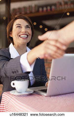 Stock Image - Business people shaking hands in cafe. Fotosearch