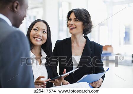 Picture - Business people talking in lobby. Fotosearch