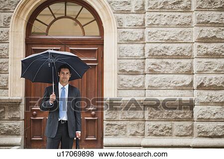 Businessman carrying umbrella on street View Large Photo Image Stock Photo - Businessman carrying umbrella on street. Fotosearch