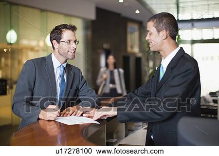 Stock Image - Businessman checking into hotel. Fotosearch