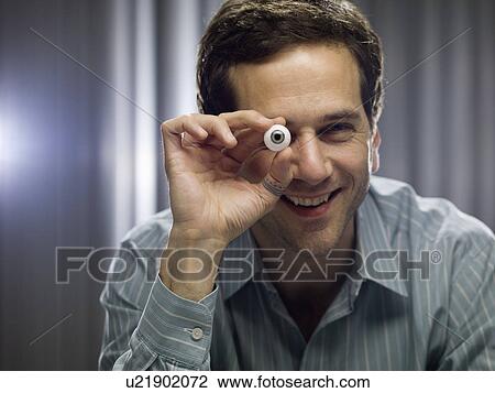Stock Image - Businessman holding glass eye. Fotosearch