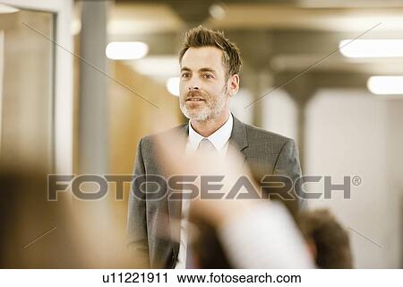 Stock Image - Businessman hosting seminar in office. Fotosearch