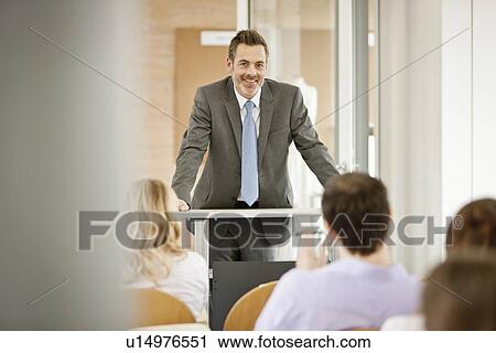 Stock Image - Businessman hosting seminar in office. Fotosearch