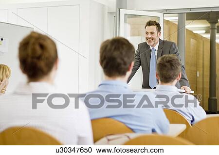 Stock Image - Businessman hosting seminar in office. Fotosearch