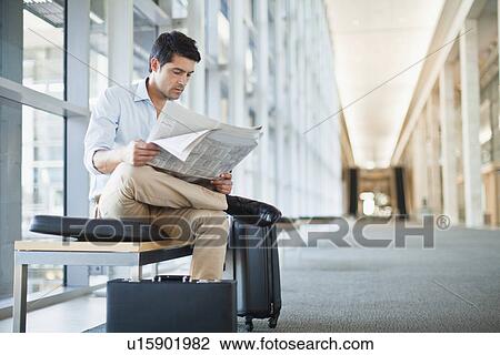 Stock Image - Businessman reading newspaper on bench. Fotosearch