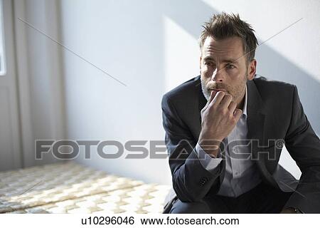 Stock Photograph - Businessman sitting on bench in office. Fotosearch
