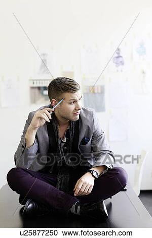 Stock Image - Businessman sitting on desk. Fotosearch