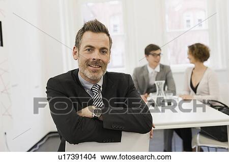 Businessman smiling in office View Large Photo Image Picture - Businessman smiling in office. Fotosearch