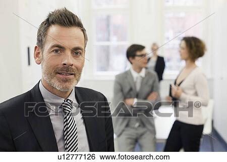 Businessman smiling in office View Large Photo Image Stock Photograph - Businessman smiling in office. Fotosearch