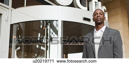 Businessman standing outside building View Large Photo Image Stock Image - Businessman standing outside building. Fotosearch