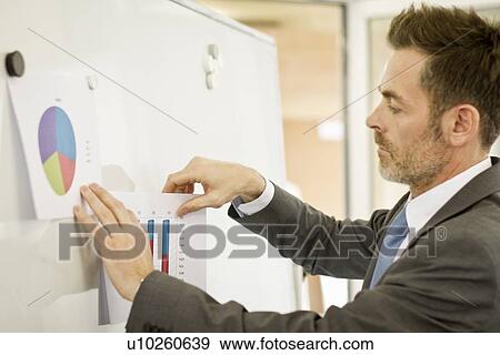 Stock Photo - Businessman tacking up posters in office. Fotosearch
