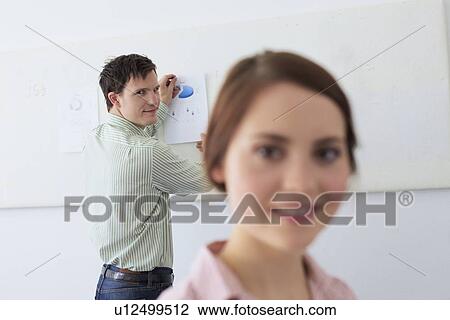 Stock Image - Businessman tacking up sign in office. Fotosearch