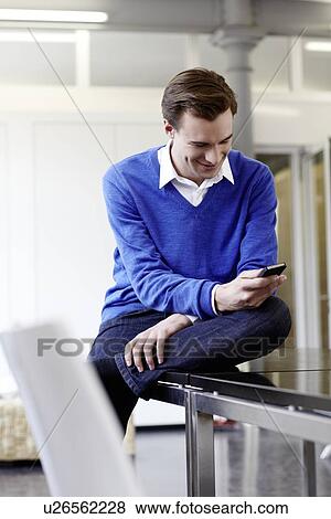 Stock Photo - Businessman using cell phone on desk. Fotosearch