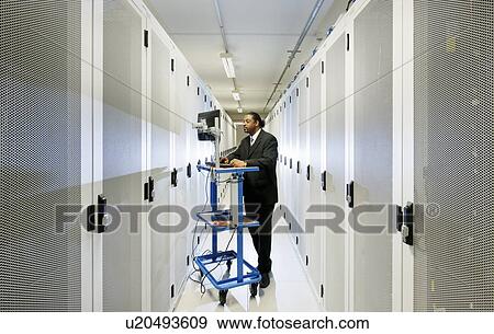 Stock Photo - Businessman using computer with servers. Fotosearch