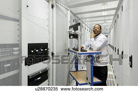 Stock Photography - Businessman using computer with servers. Fotosearch