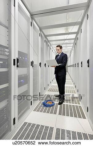 Businessman using laptop in server room View Large Photo Image Stock Image - Businessman using laptop in server room. Fotosearch