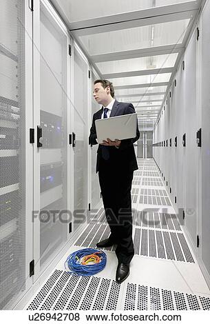 Businessman using laptop in server room View Large Photo Image Stock Photo - Businessman using laptop in server room. Fotosearch