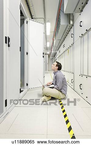 Businessman using laptop in server room View Large Photo Image Stock Photography - Businessman using laptop in server room. Fotosearch