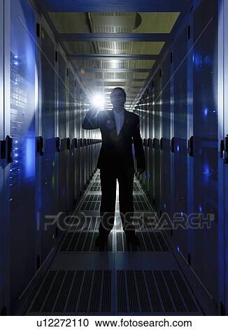 Stock Image - Businessman walking in server room. Fotosearch