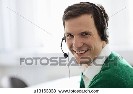 Businessman wearing headset in office View Large Photo Image Stock Photo - Businessman wearing headset in office. Fotosearch